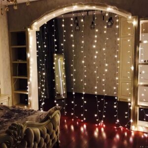 Cortina de luces led con control remoto de tres por dos metros instalada sobre un arco arquitectonico de un dormitorio iluminando el suelo de madera