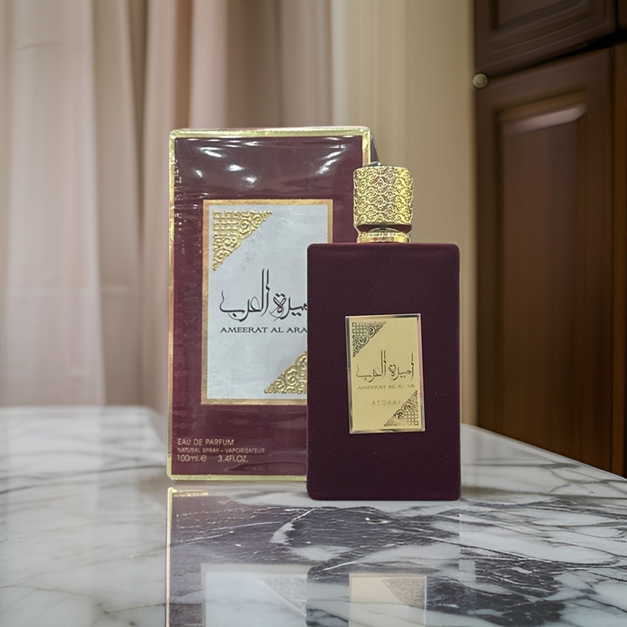 Perfume Árabe Ameerat Al Arab Rojo Lattafa 👑 Fotografia real del perfume arabe ameerat al arab rojo de cien mililitros de la marca lattafa mostrando su frasco rectangular de terciopelo rojo con tapon dorado junto a su caja de lujo