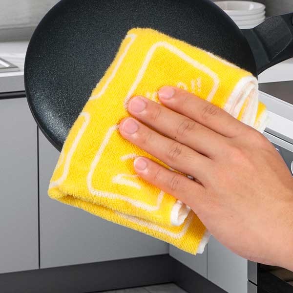 Limpieza de Crepera Sokany SK-5208 ✨ Mano limpiando la superficie circular negra antiadherente de la crepera electrica portatil Sokany SK-5208 con un paño amarillo